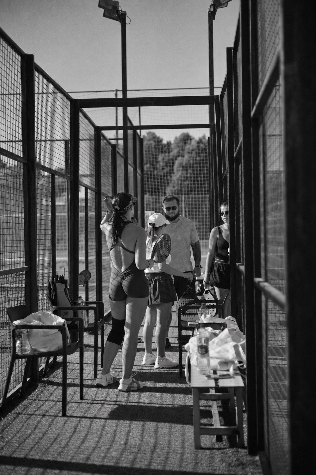 Players with rackets chatting between the padel courts
